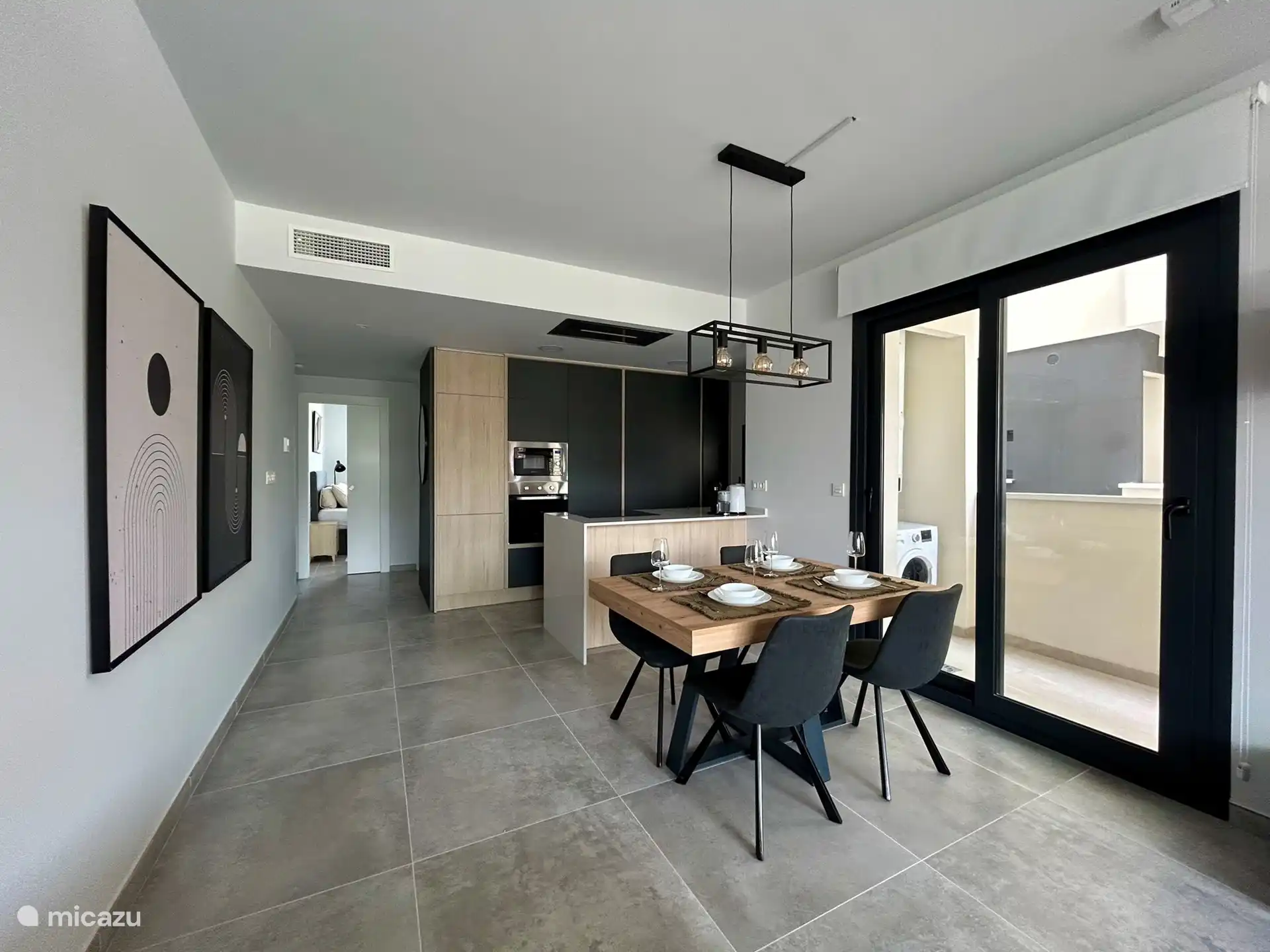 La salle à manger et la cuisine spacieuses et lumineuses, avec des portes coulissantes sur le côté de l’appartement menant au balcon supplémentaire où se trouve la machine à laver. Il y a beaucoup d’espace sur le balcon pour le séchoir. 