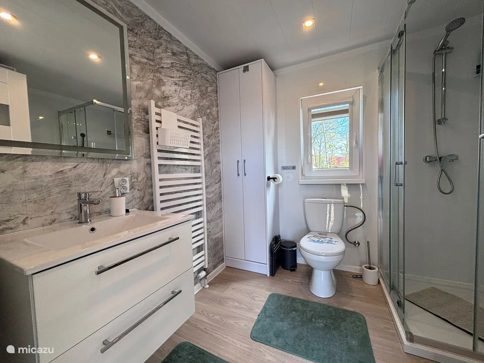 Amplio cuarto de baño con tocador, WC y amplia ducha.