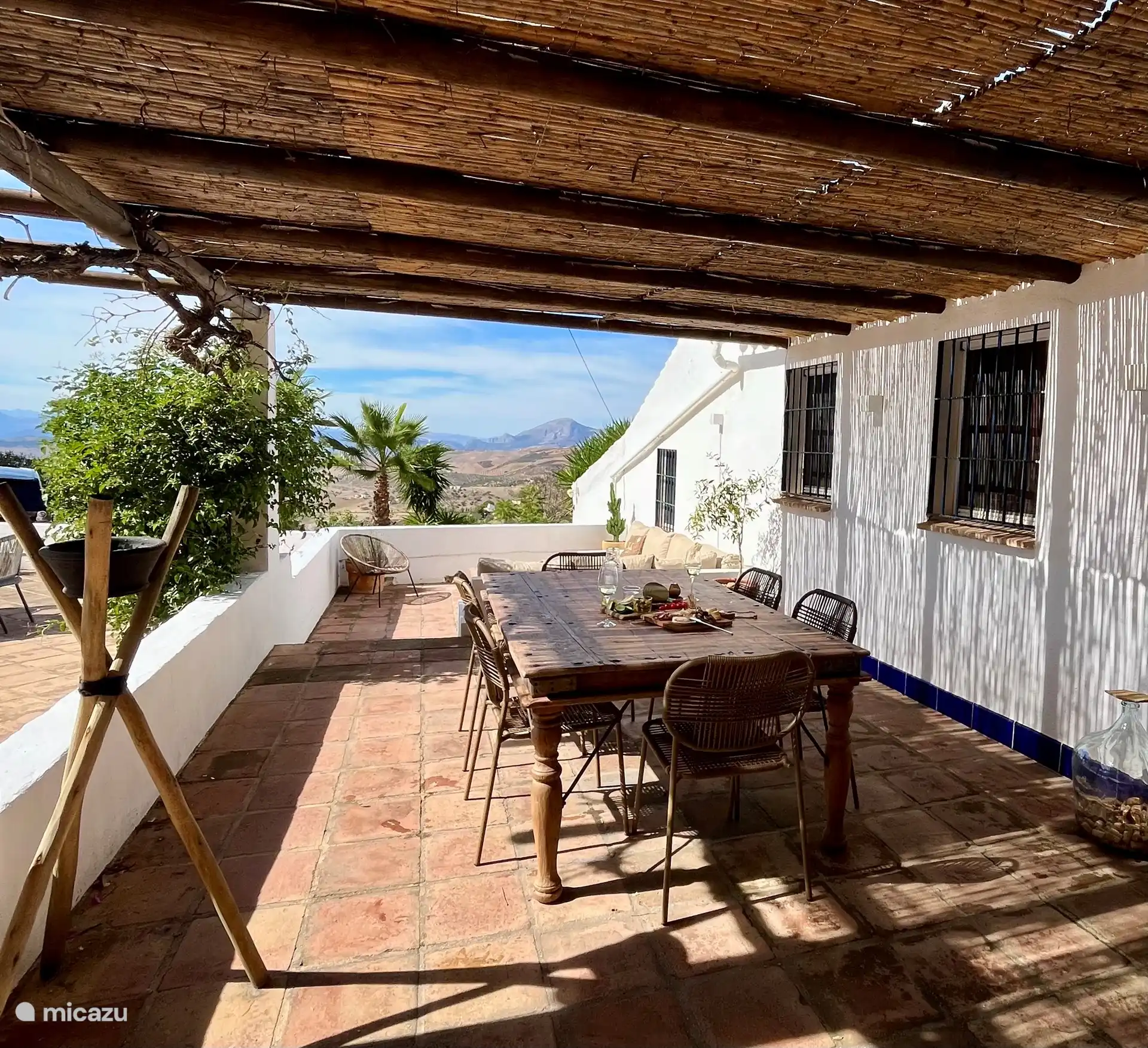 Überdachte Terrasse mit antikem Esstisch.