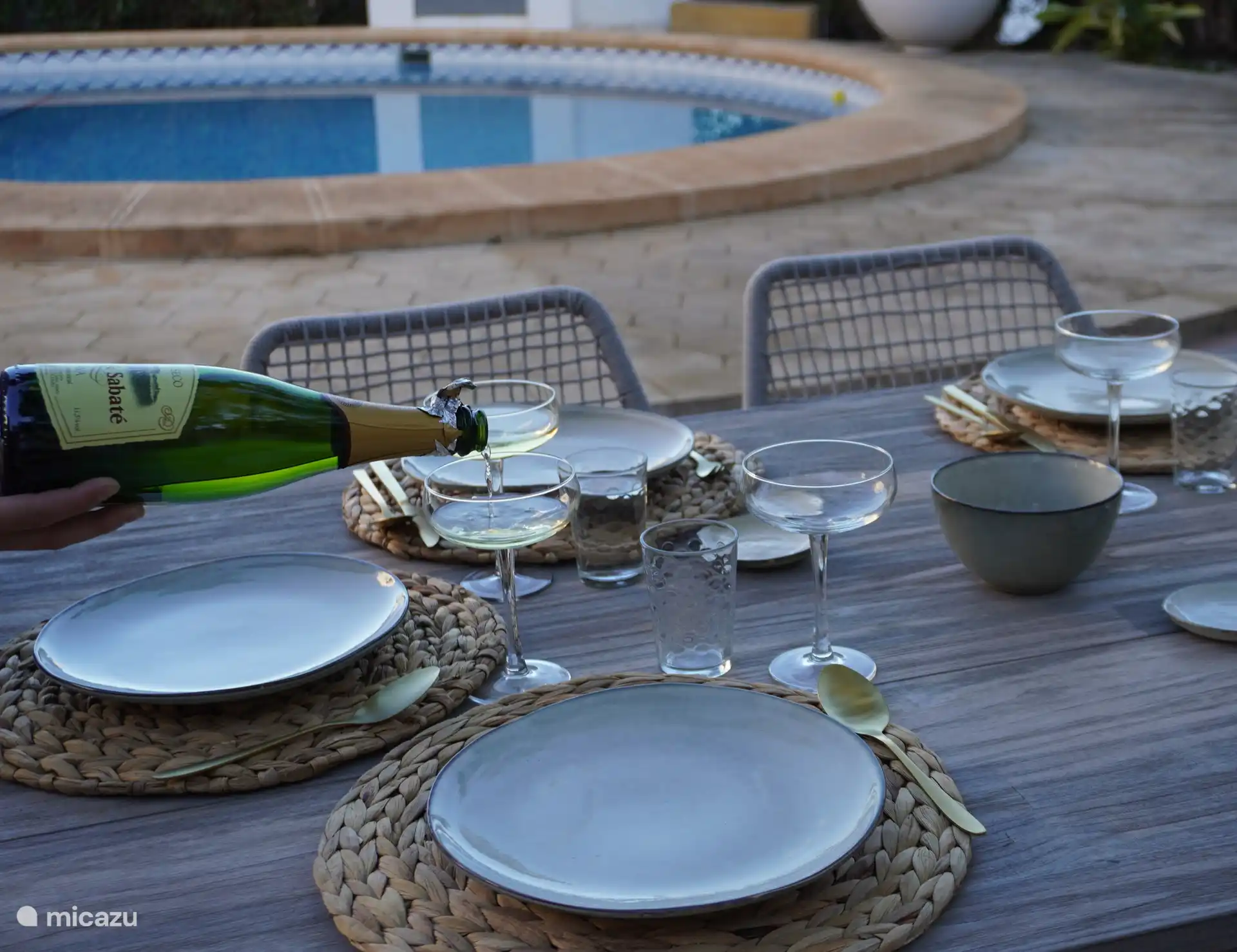 Listo para una cena romántica con una copa de delicioso cava español en la terraza frente a la cocina exterior, al borde de la piscina. El jardín también está agradablemente iluminado por la noche.