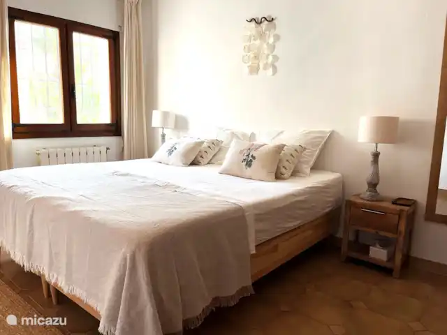 Villa Salvia en España, Costa Blanca, Benissa - villa El 'dormitorio principal' en la planta superior: un amplio dormitorio con armario empotrado, TV y vistas a las palmeras del jardín.