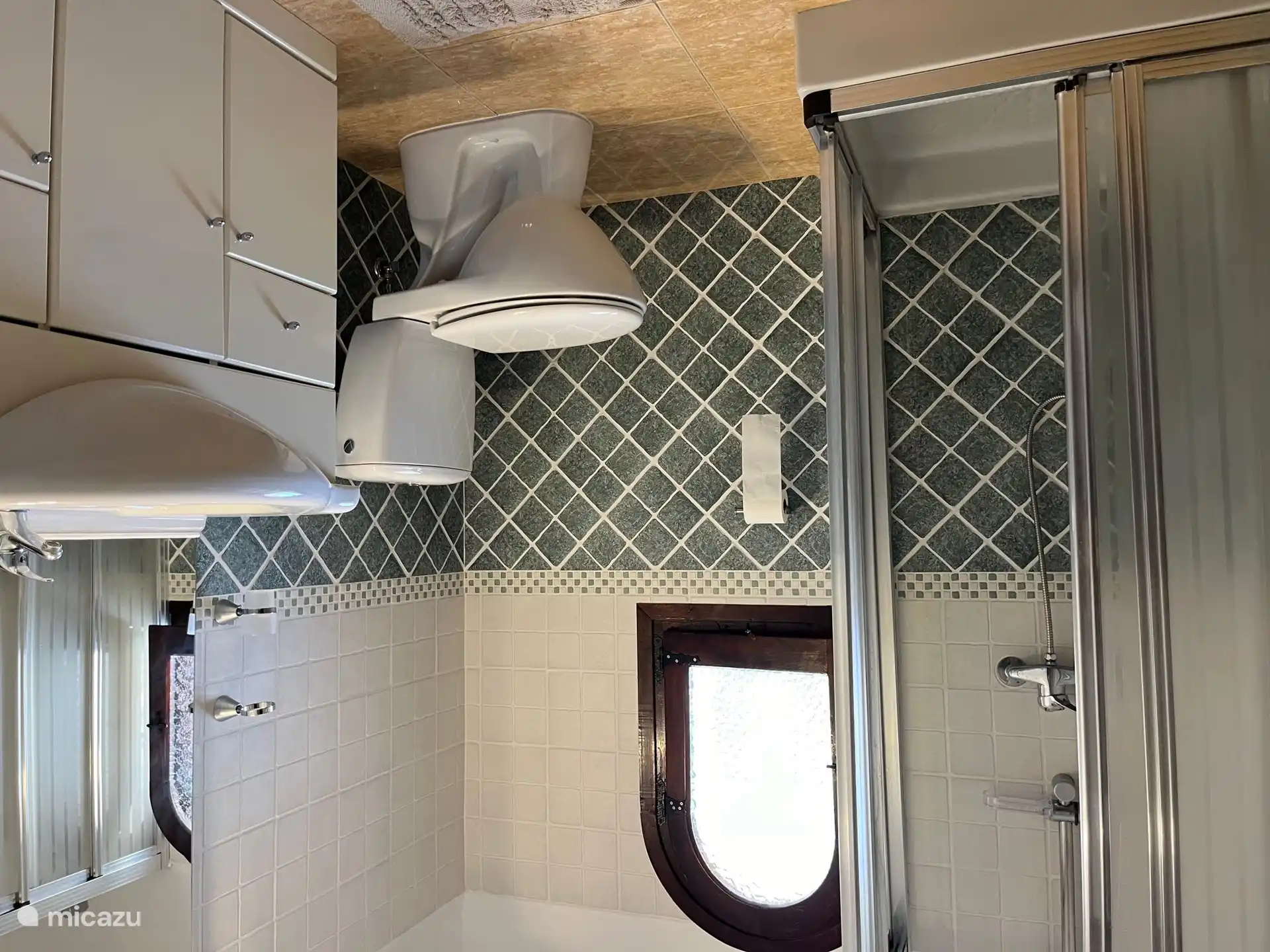 Uno de los baños de la planta baja, con ducha, inodoro, lavabo con mueble de lavabo y secador de pelo.