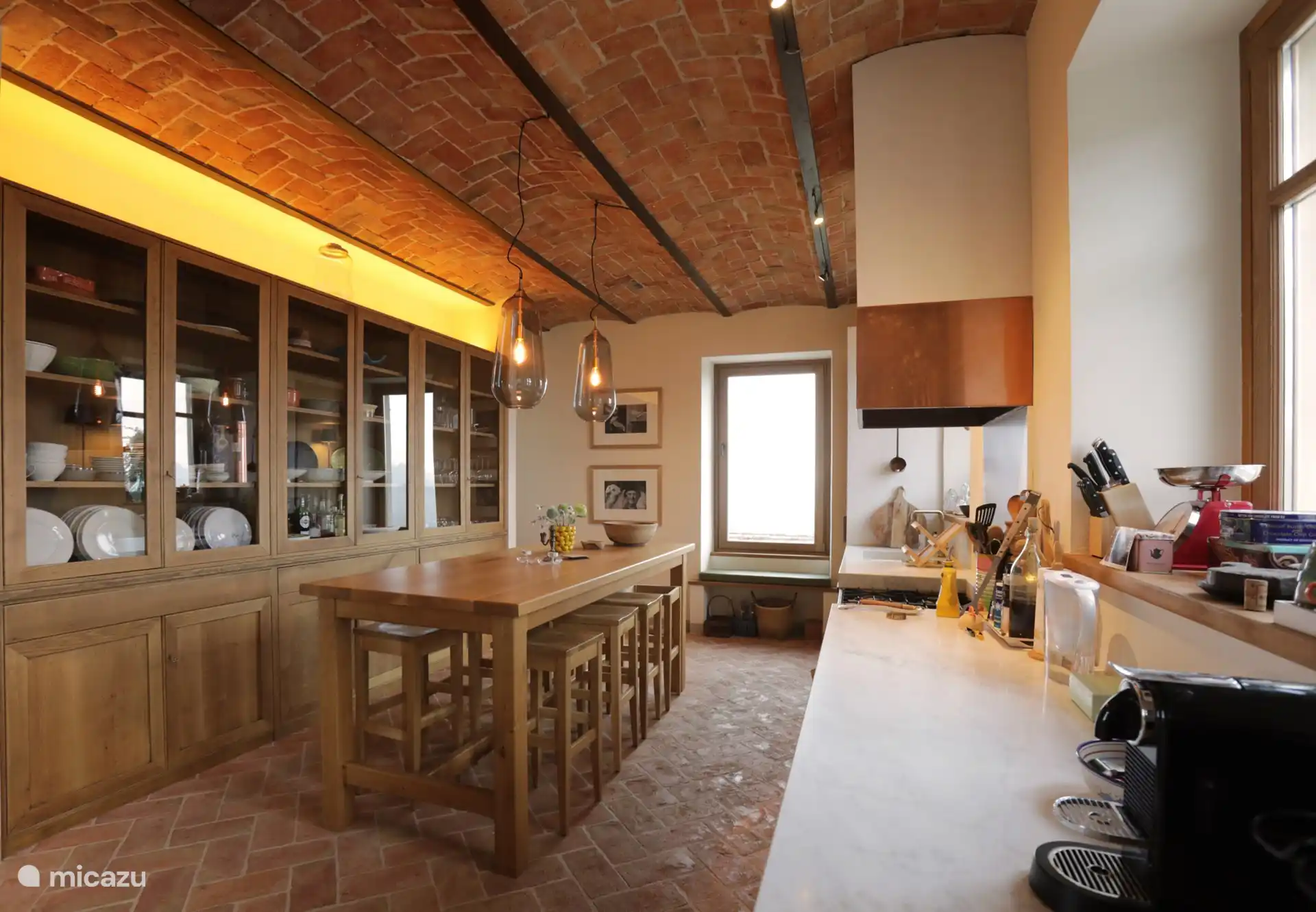 Keuken met een ruime bartafel, groot marmeren aanrechtblad en grote kast met servies. 