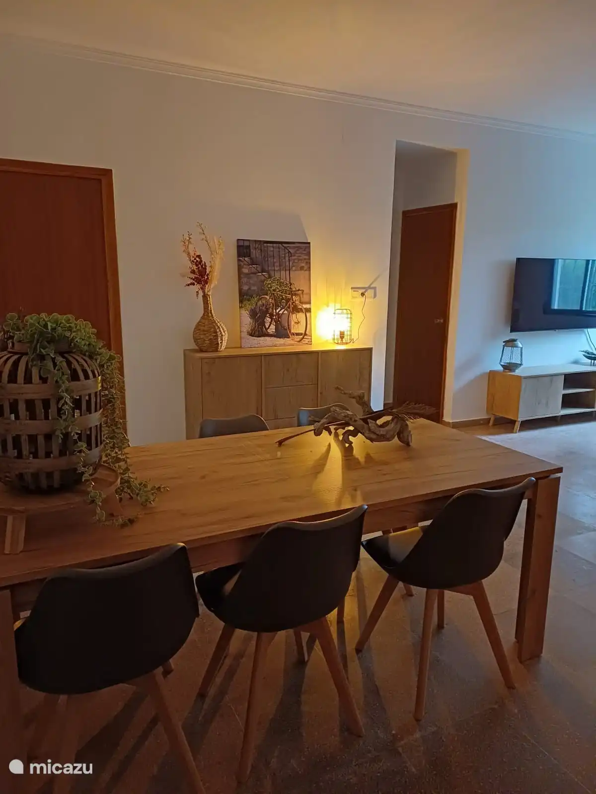Ein anderer Blick im Wohnzimmer. Das Sideboard ist vom Esstisch aus sichtbar. Auch der Fernseher und der TV-Schrank sind sichtbar. Die Tür auf der linken Seite führt zu einem Doppelzimmer.