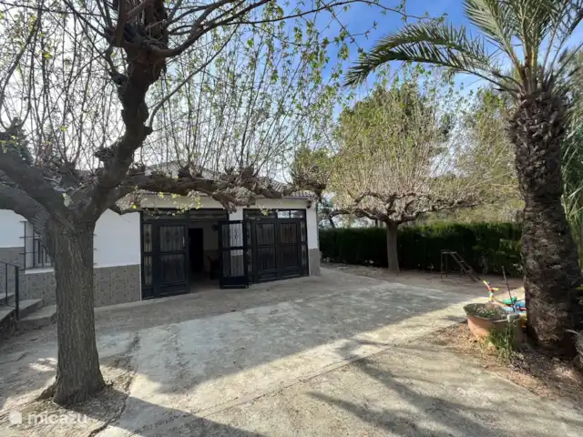 Villa Morera en España, Valencia, Albaida - villa En esta foto se puede ver el frente de la casa con las puertas cerradas (período invernal sin vegetación). Las puertas están equipadas con malla HOR, por lo que el invernadero está libre de plagas. También puedes sentarte aquí cuando llueve.