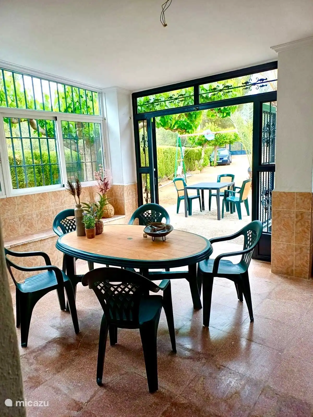 Sitzecke im/unter dem Wintergarten mit Blick auf den Vorgarten und die lange Auffahrt. Alles wunderbar grün und weitläufig.