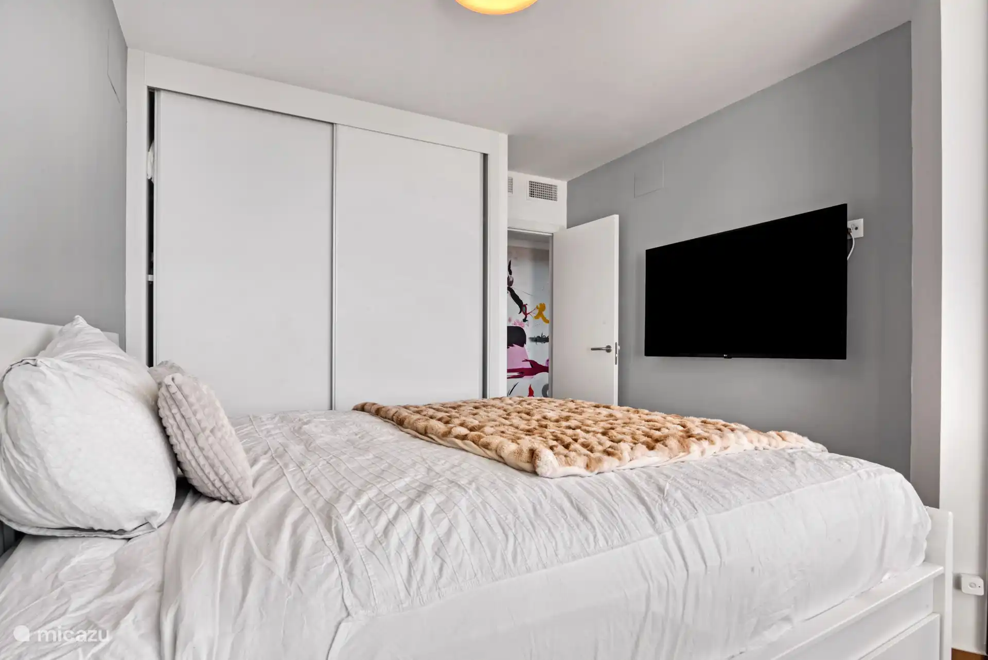 Another perspective of the middle bedroom with its own closet and its own smart TV.