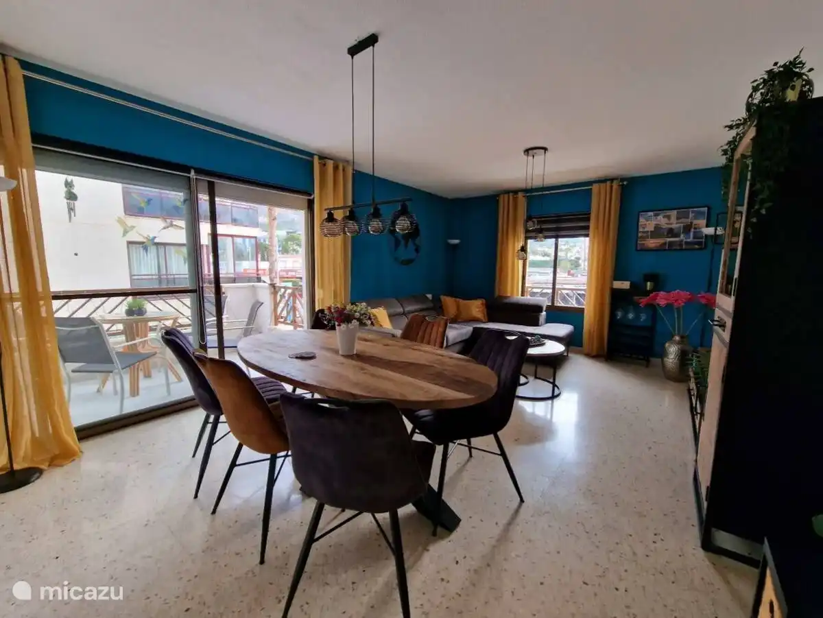 Wohnzimmer mit großem Esstisch und gemütlicher Sitzecke mit Smart-TV