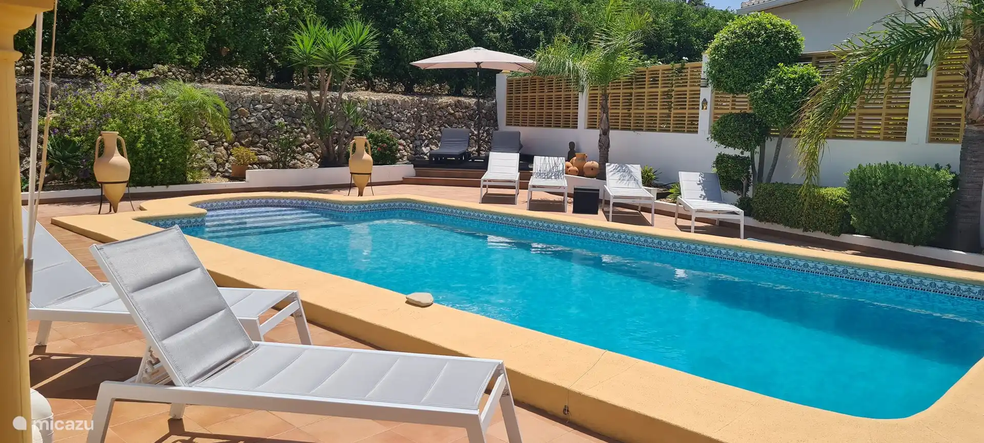 6 Liegest&#252;hle und 2 Sonnenschirme am Pool