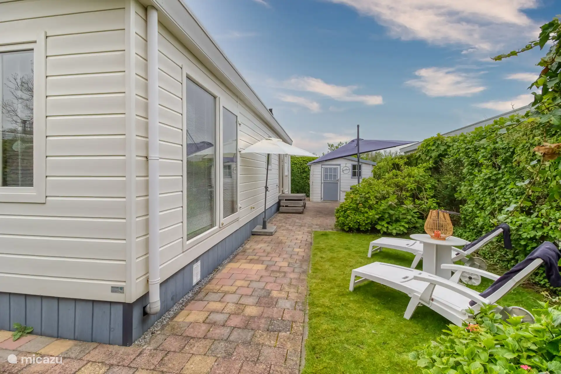 heerlijke privacy biedende achtertuin met veel zon, gelegen op het zuiden en voorzien van terras, stoelen, parasols en ligstoelen