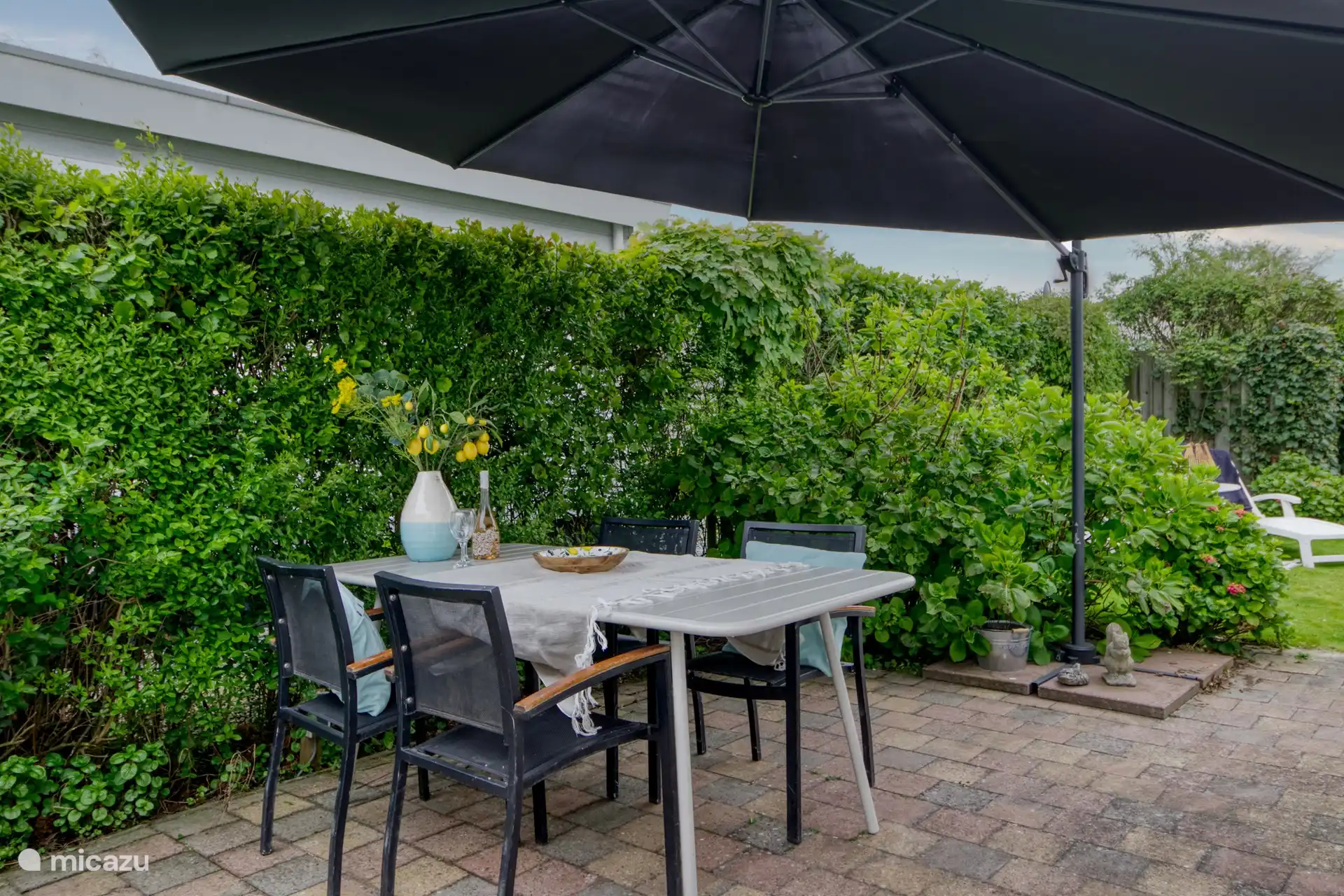 heerlijke privacy biedende achtertuin met veel zon, gelegen op het zuiden en voorzien van terras, stoelen, parasols en ligstoelen