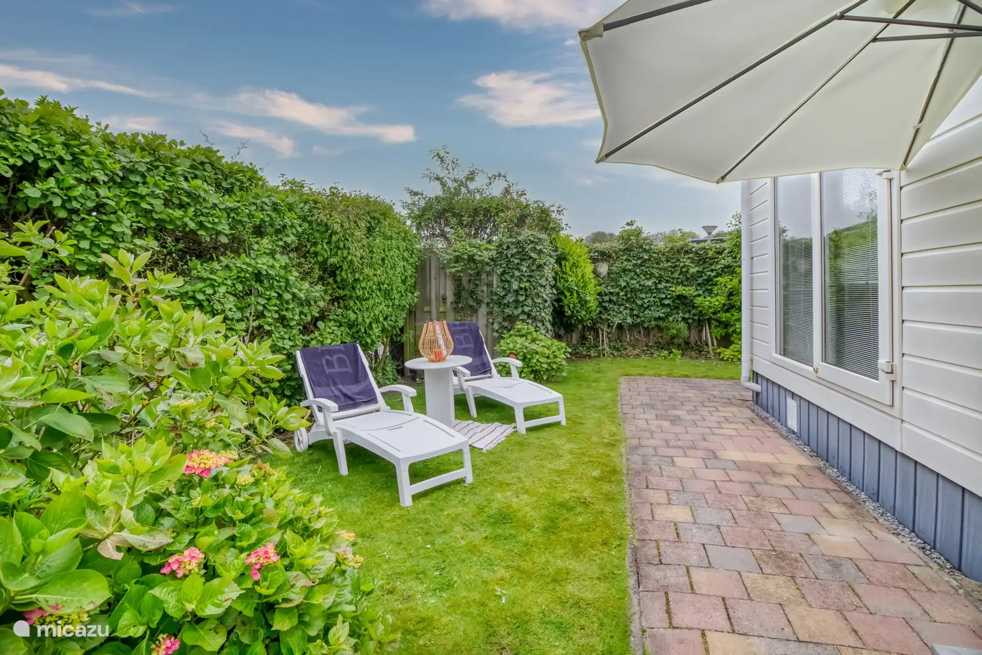 heerlijke privacy biedende achtertuin met veel zon, gelegen op het zuiden en voorzien van terras, stoelen, parasols en ligstoelen