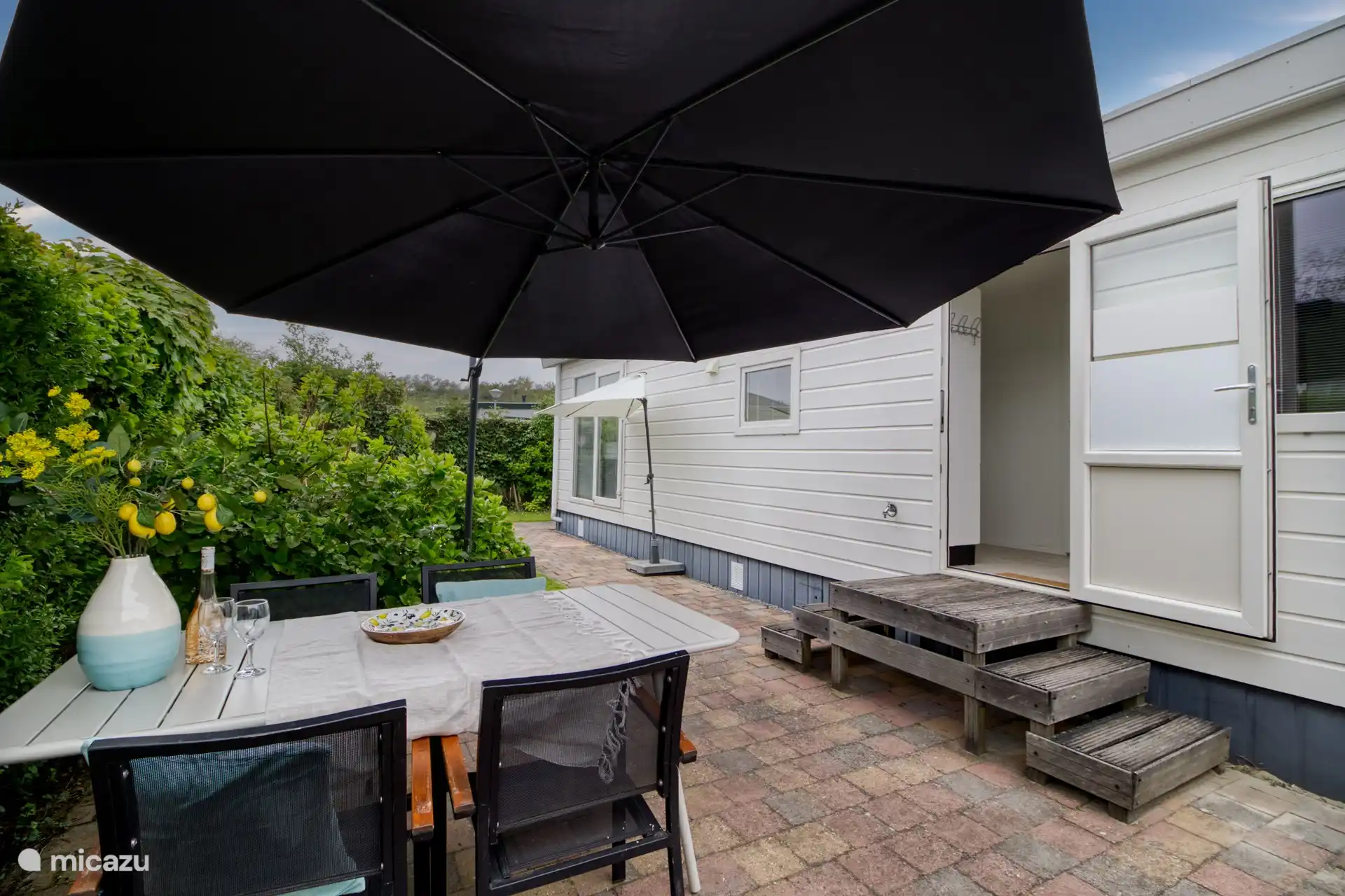 heerlijke privacy biedende achtertuin met veel zon, gelegen op het zuiden en voorzien van terras, stoelen, parasols en ligstoelen