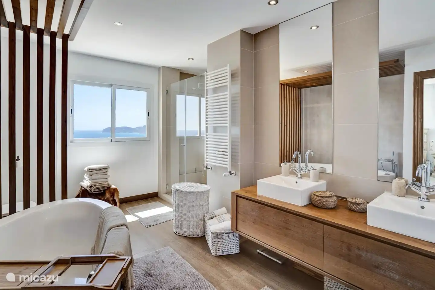 Baño en suite de los dormitorios principales con bañera, doble lavabo y cabina de ducha para dos personas con cabezal de lluvia... todo con vista al mar.