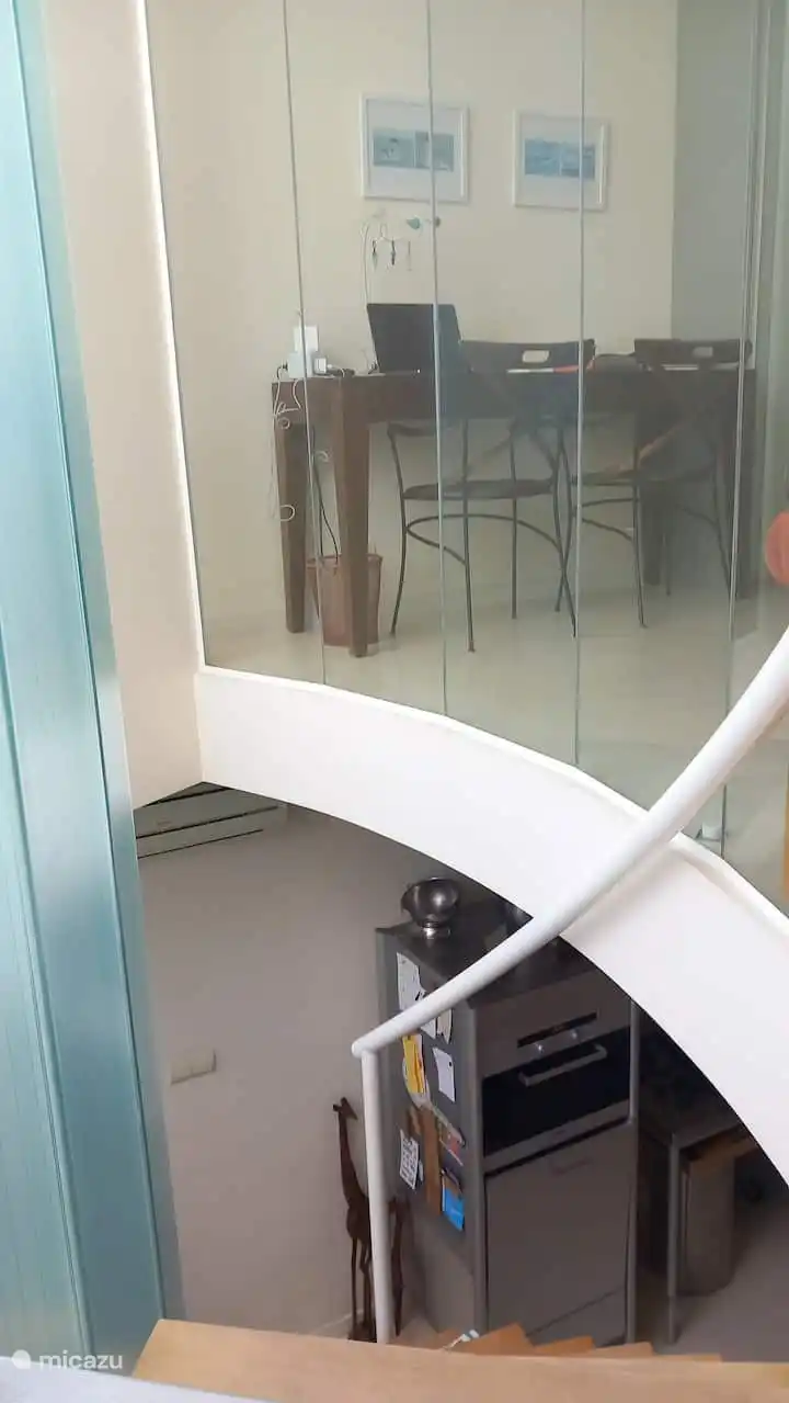 Holztreppe in den ersten Stock und Blick in das Arbeits-/Schlafzimmer (Computeranschluss, WLAN, Arbeitstisch, zwei Stühle, kleine Bibliothek mit Büchern und bequemes Schlafsofa.