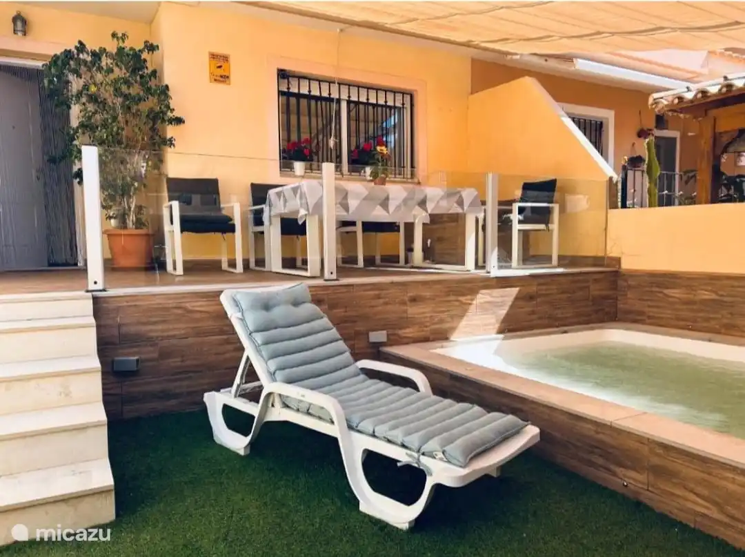 Deze afbeelding toont de gevel van een huis waar u buiten kunt lunchen en dineren. De buitenruimte is uitgerust met een tafel en verschillende stoelen, waardoor een ideale ruimte ontstaat om te genieten van aangename momenten in gezelschap. De tafel is versierd met een tafelkleed en de stoelen zijn modern