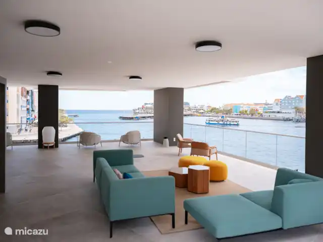 Location de Vacances Curaçao, Curaçao-Centre, Willemstad, appartement - L’appartement de luxe The Wharf MT Le salon avec une vue panoramique sur la Handelskade, le pont flottant et le Waaigat.