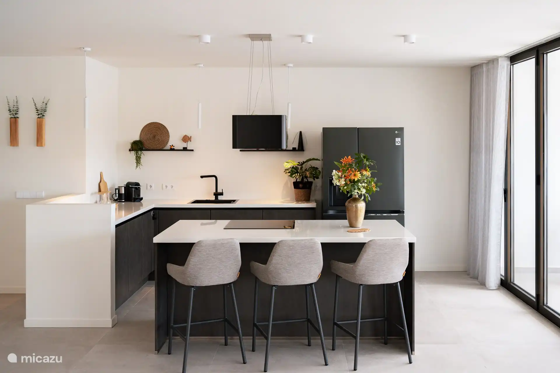 Luxuriöse Küche mit Insel mit bequemen Barhockern für gemütliches gemeinsames Essen. Die Küche ist mit Backofen/Mikrowelle, Induktionskochfeld und amerikanischem Kühlschrank mit Wasser-/Eiswürfelspender ausgestattet.