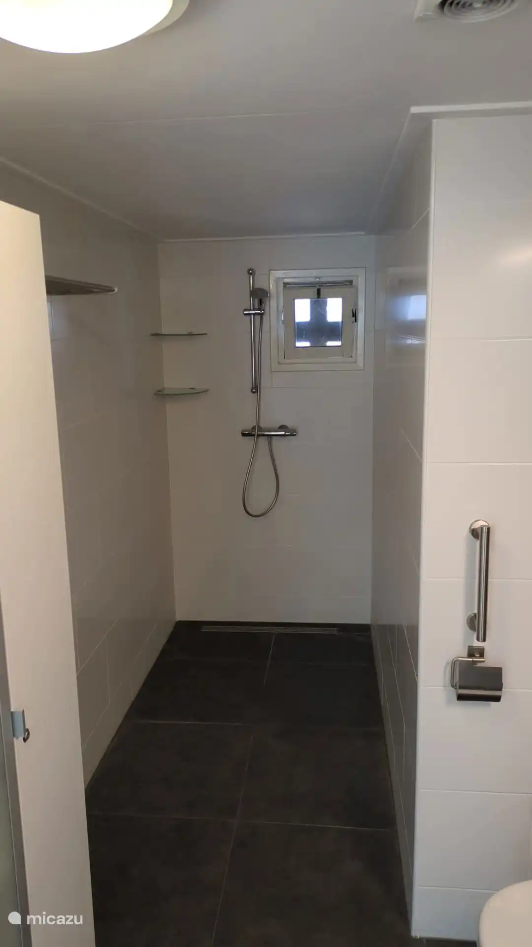 Das geräumige Badezimmer verfügt über eine Fußbodenheizung. Die ebenerdige Dusche ist 120 cm breit. Es gibt einen Spiegelschrank und einen Regalschrank zur Aufbewahrung von Hygieneartikeln und Handtüchern.