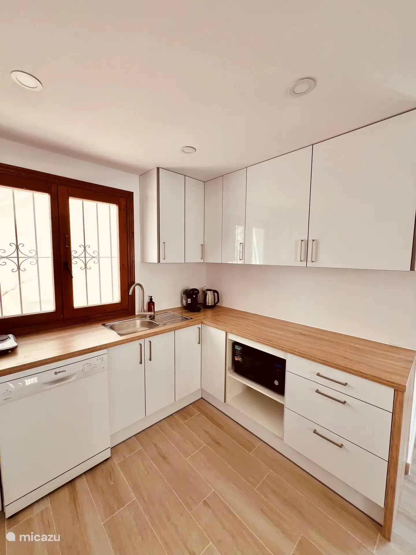 Moderne nieuwe keuken met vaatwasser,  kookplaat, koelkast met vries gedeelte, airfryer, magnetron, oven, koffiezet apparaat met cupjes, waterkoker.