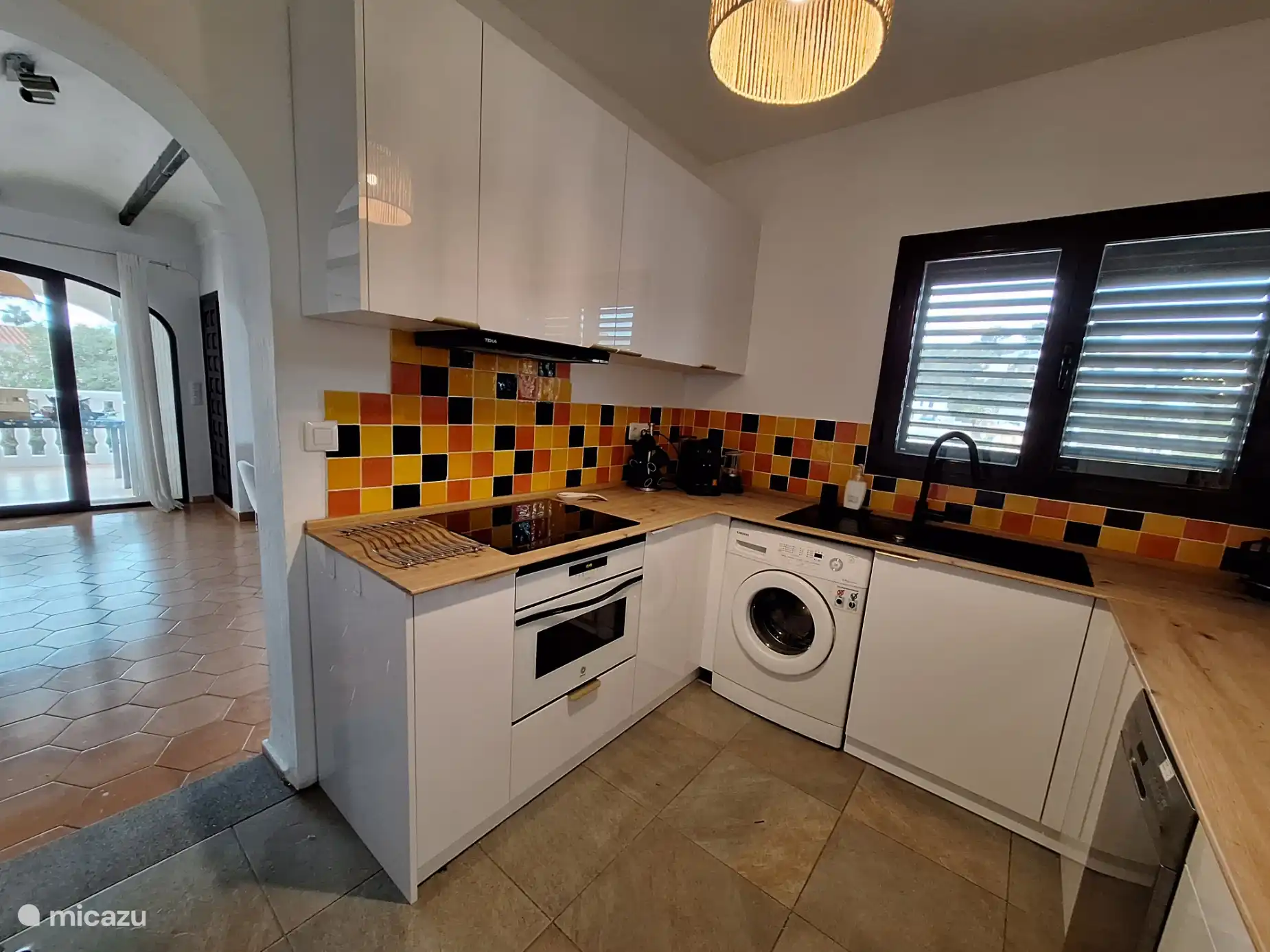 Moderne Küche mit Induktionskochfeld, Kombi-Backofen (Mikrowelle und Backofen), Dunstabzugshaube, Geschirrspüler, Waschmaschine und Kühlschrank mit Gefrierfach