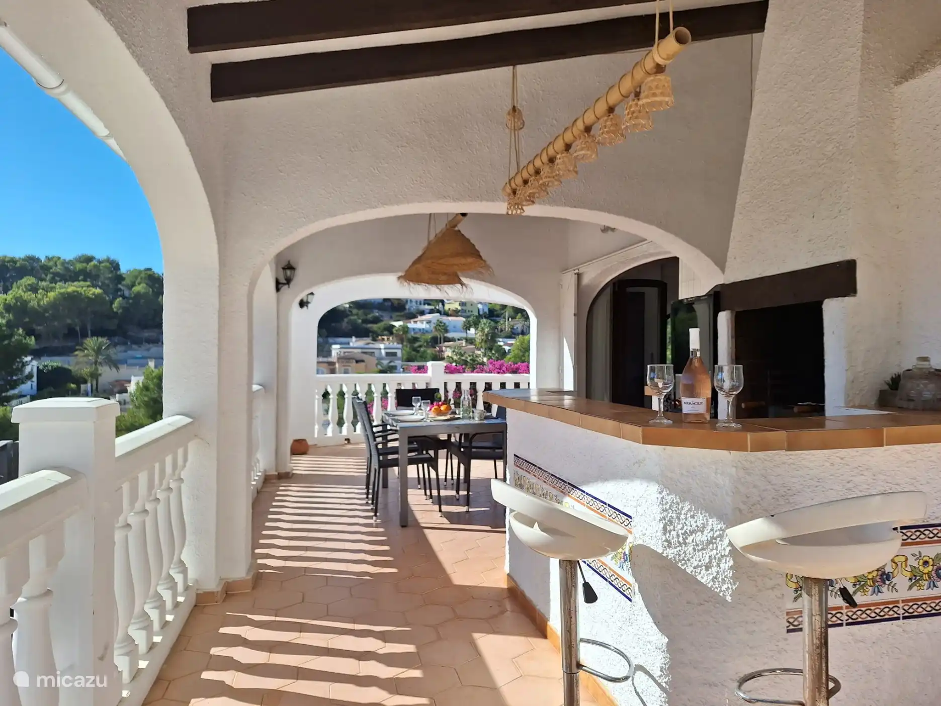 Geräumige überdachte Terrasse mit Grillplatz, Bar und Esstisch und Stühlen.