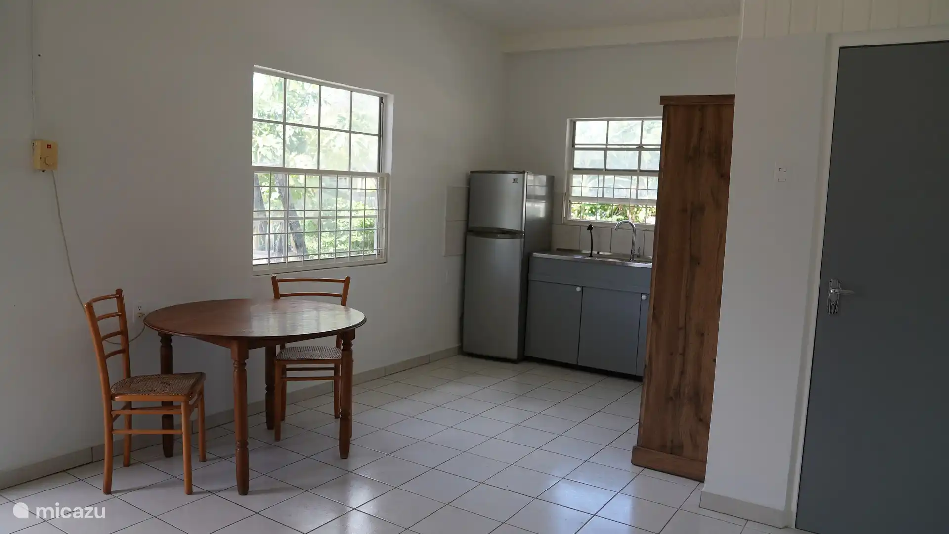 Küche mit Kühlschrank, Gefrierschrank, Gasherd, Backofen, Wasserkocher, Klimaanlage, Ventilator und Kühlbox sowie Esstisch für zwei Personen