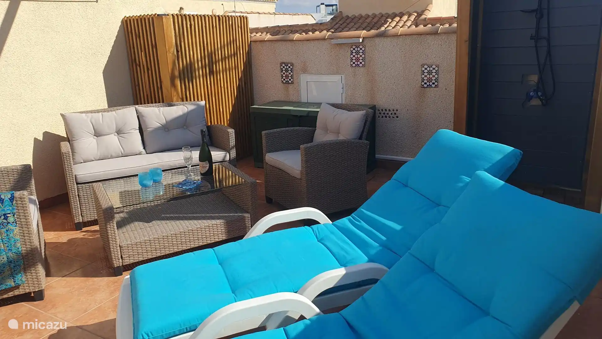 Terrasse sur le toit avec sièges, chaises longues, douche extérieure de luxe et salle à manger