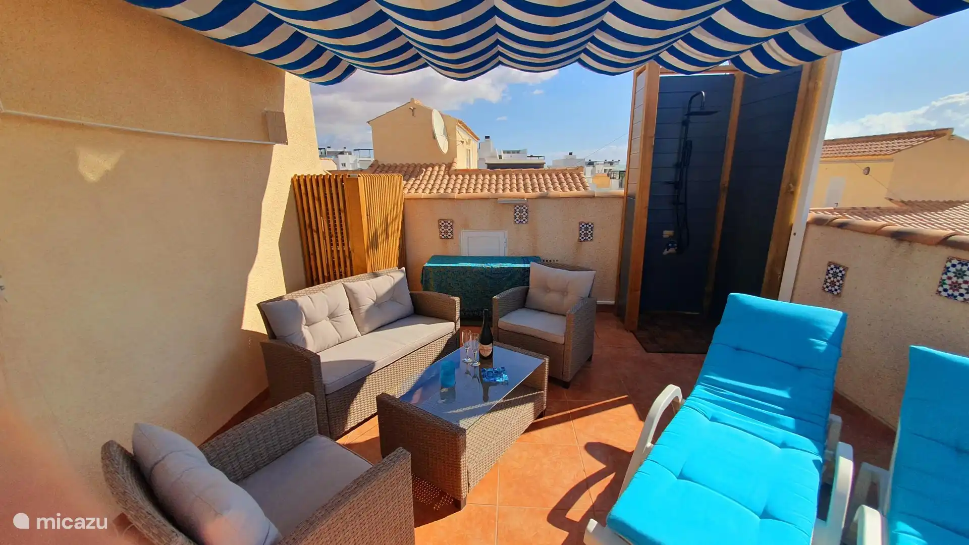 Terrasse sur le toit avec sièges, chaises longues, douche extérieure de luxe et salle à manger