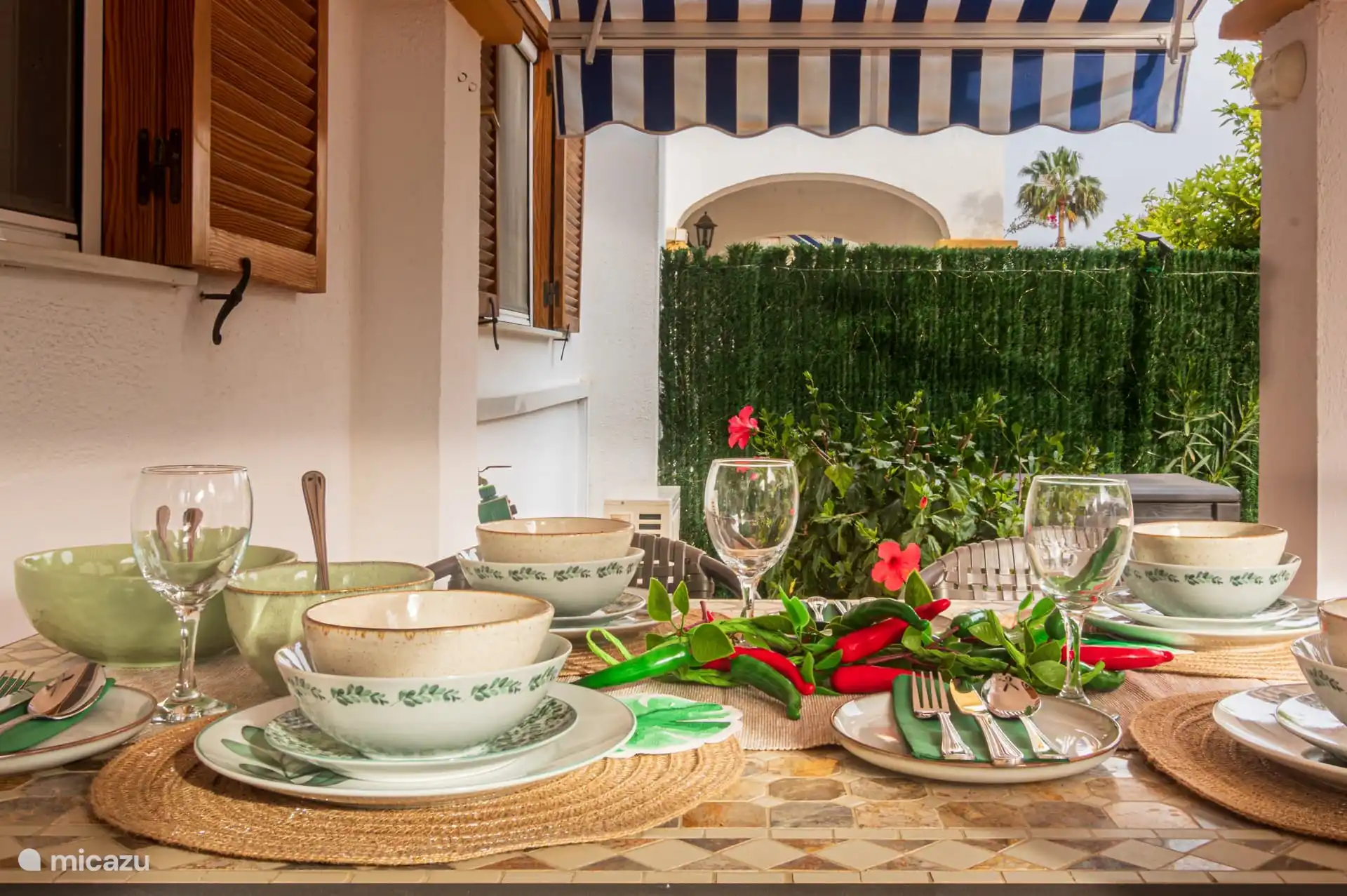 overdekt terras met eettafel, stoelen en serviesgoed