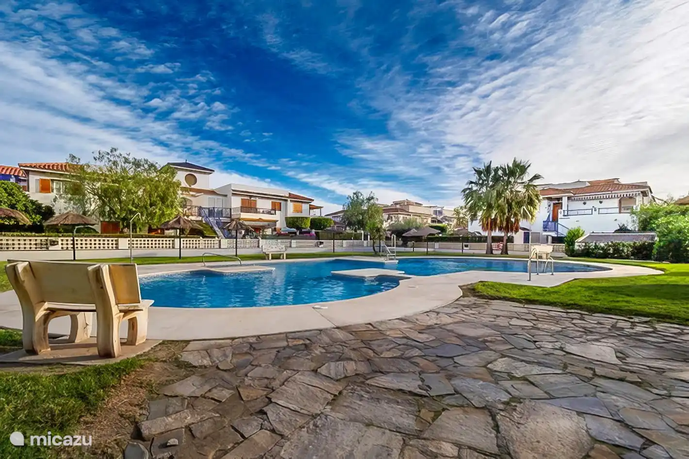 zwembad met zonneweide, parasols en ligbedden