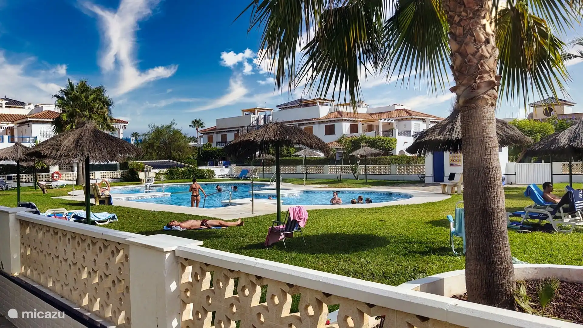 zwembad met zonneweide, parasols en ligbedden