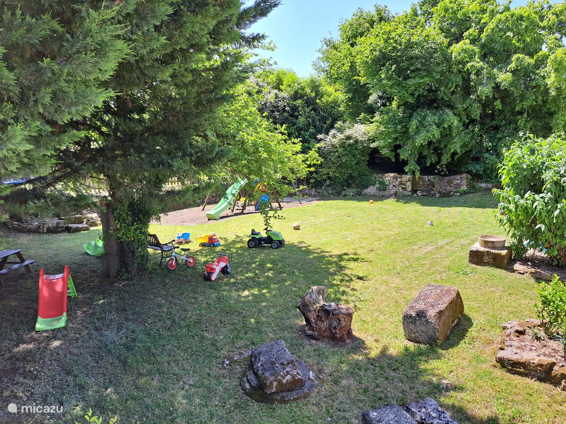 Omheinde speeltuin met zandbak, schommels, glijbaan, piratenschip en trampoline