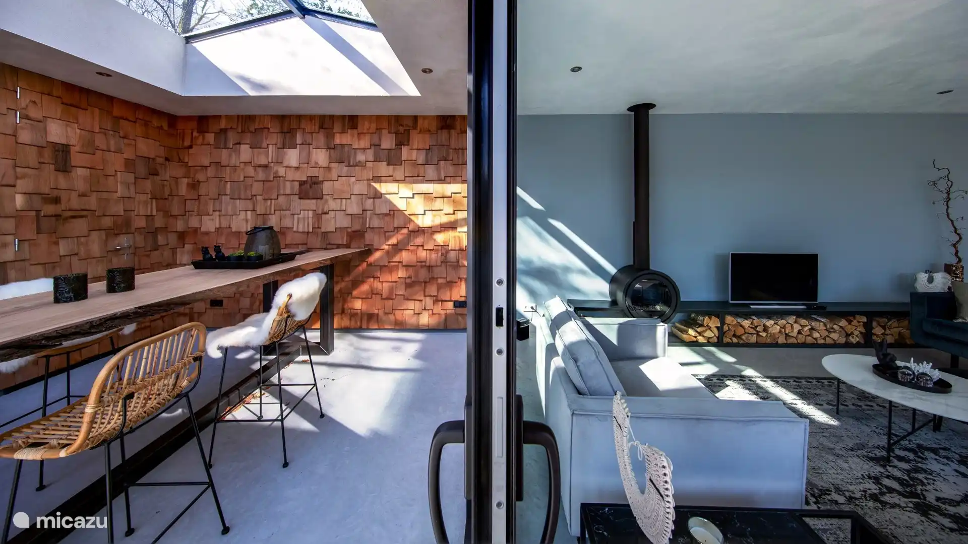 Glasschiebetüren mit dem Wohnzimmer auf der einen Seite und einer schönen Terrasse auf der anderen Seite