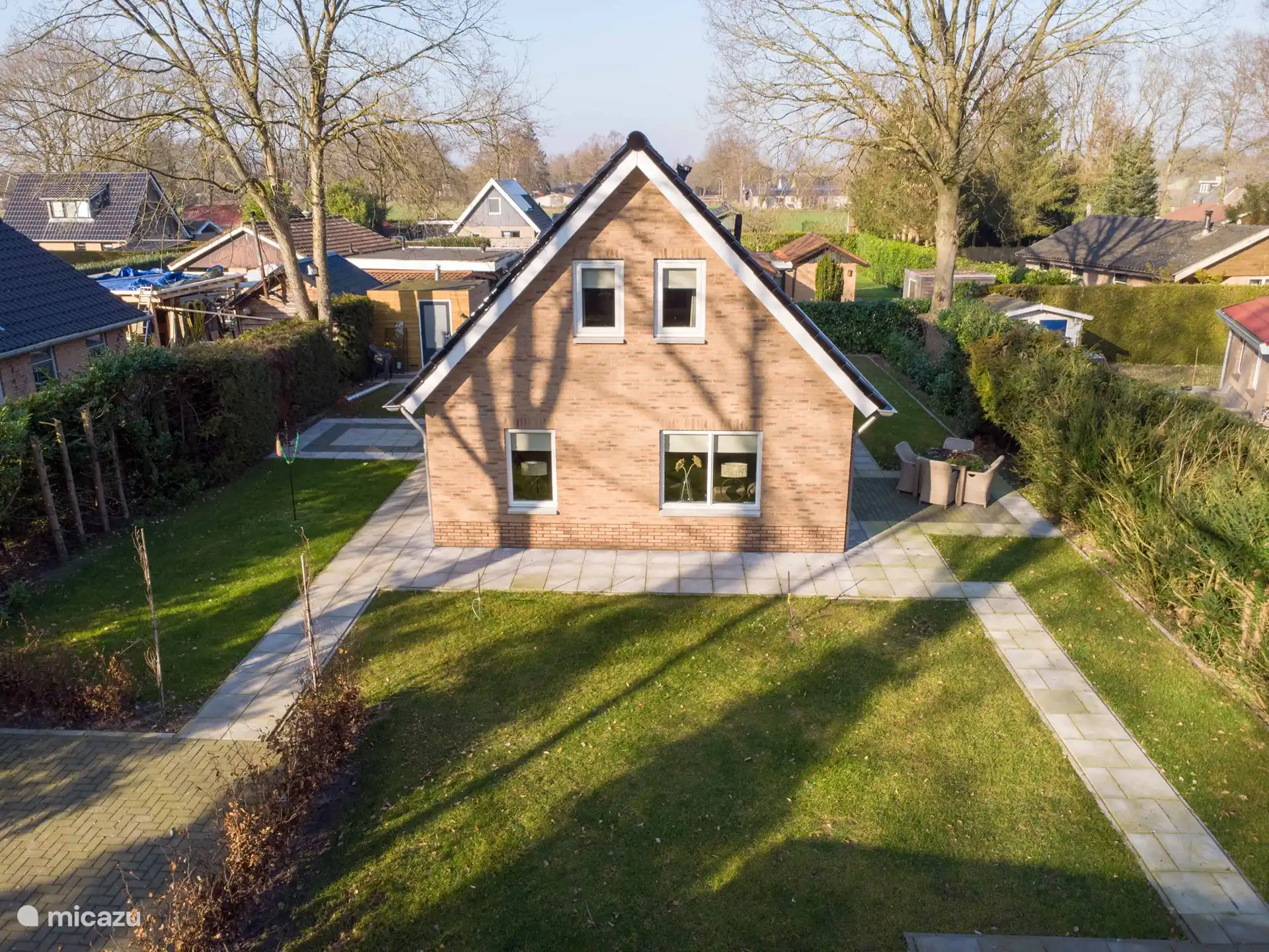 Ein Übersichtsfoto des Gartens. Der Sitz links vom Haus ist nun mit einem Tisch mit 6 Stühlen ausgestattet. Unten rechts ist ein kleiner Teil des 3. Sitzes zu sehen.