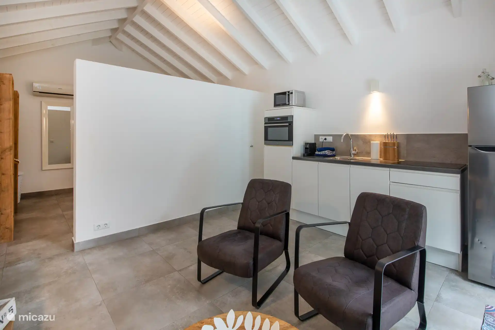 Woonkamer en keuken met twee fauteuils en TV