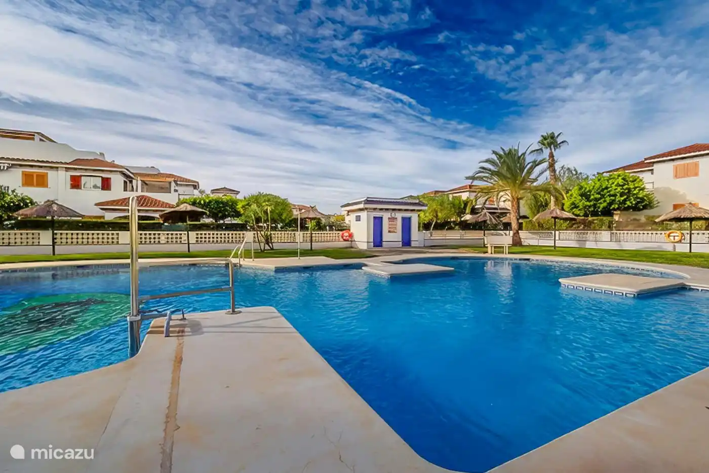 zwembad met zonneweide, parasols en ligbedden