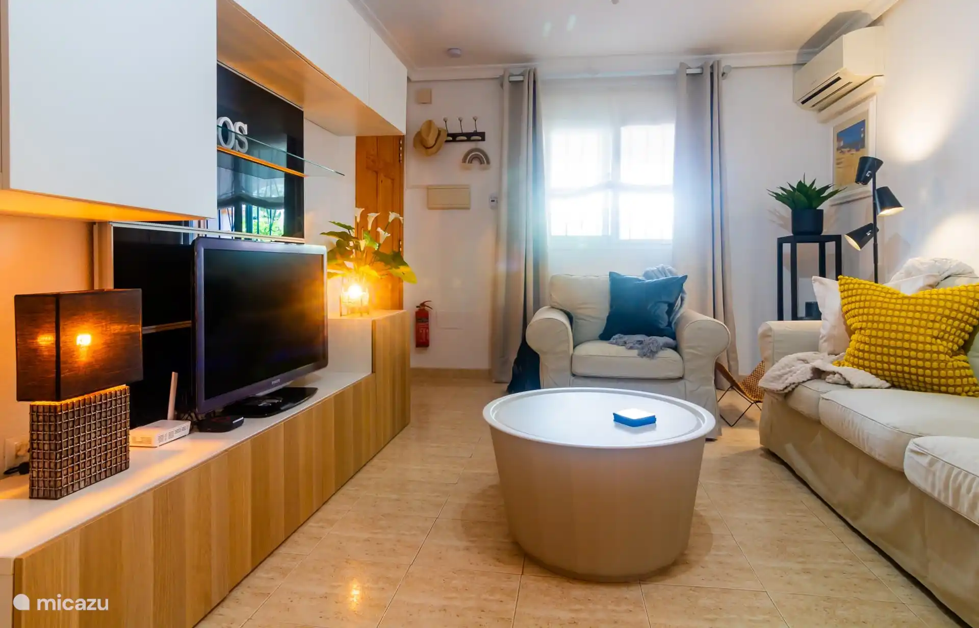 Woonkamer met televisie en voordeur. 