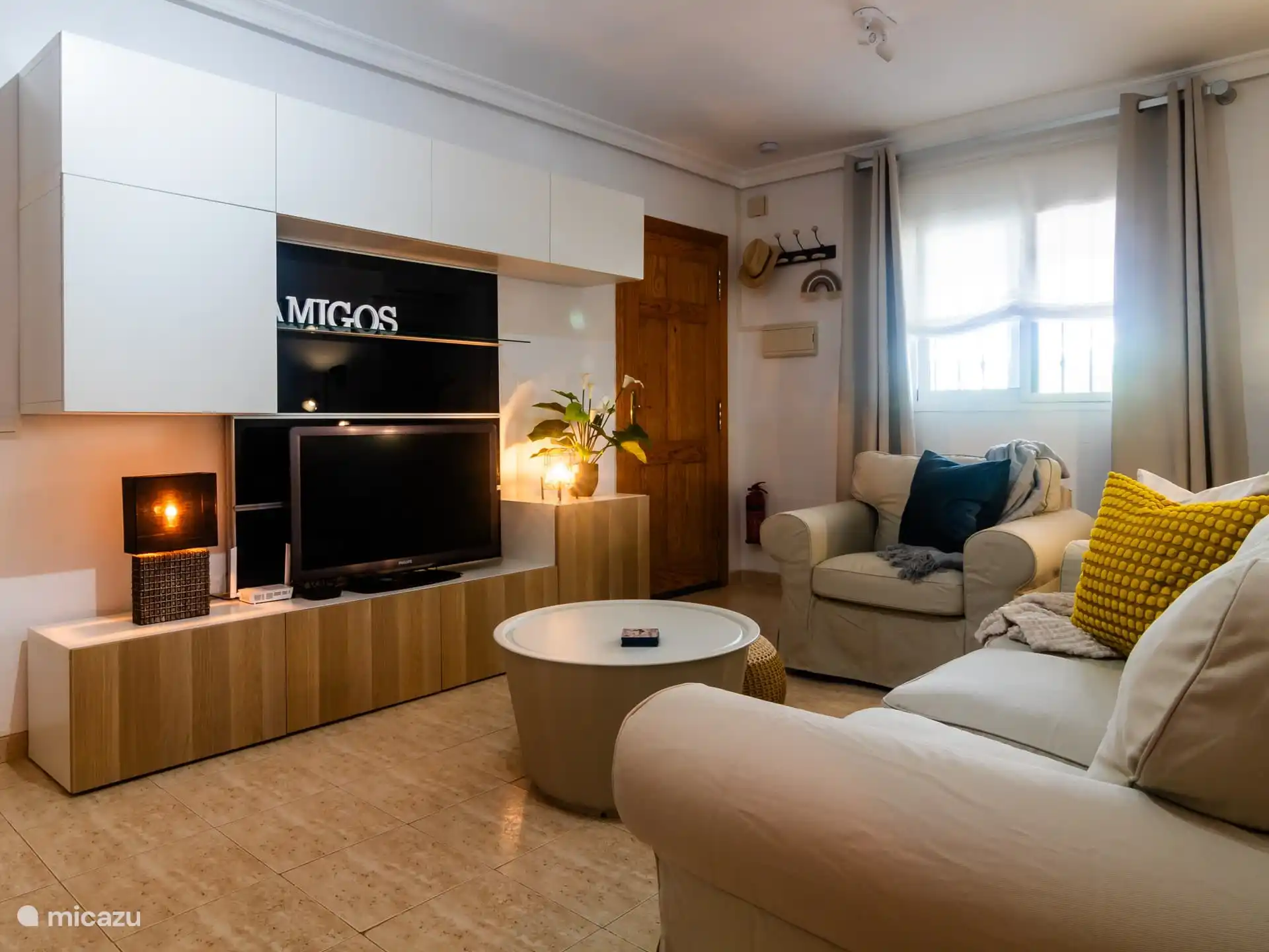 Woonkamer met televisie en voordeur. 