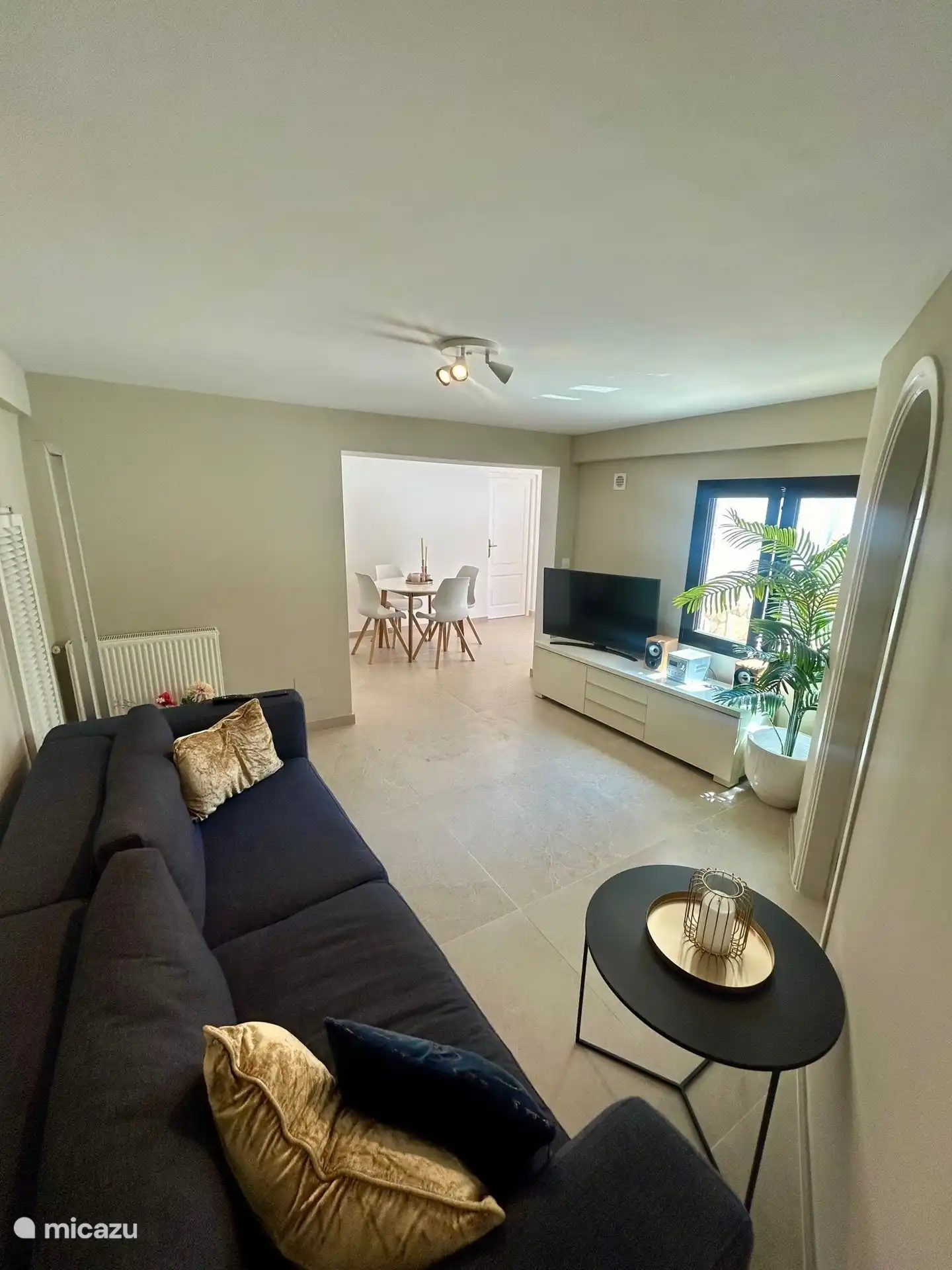 De woonkamer met zicht op het zwembad en tv met alle Nederlandse zenders.
