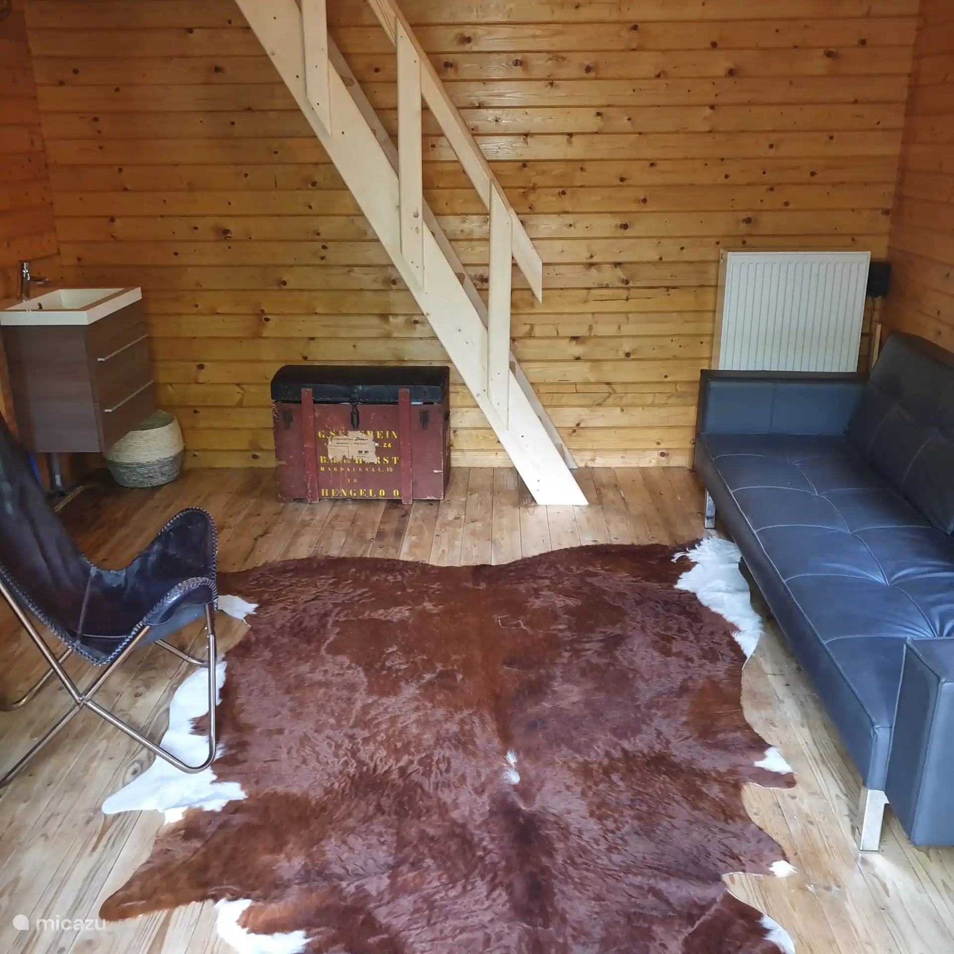 A la izquierda el rincón de lavandería con fregadero. En el misterioso cofre hay mantas y ropa de cama para el sofá cama y las escaleras van al desván para dormir.