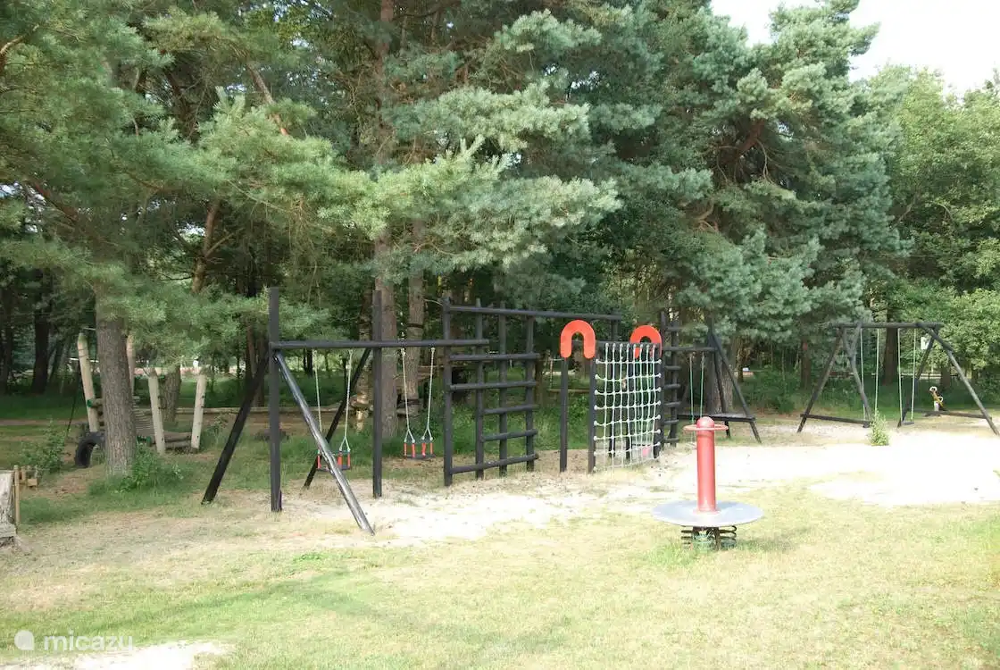 Een ruime speelweide met allerlei speel en klimrekken, goed onderhouden, pal naast het zwembad