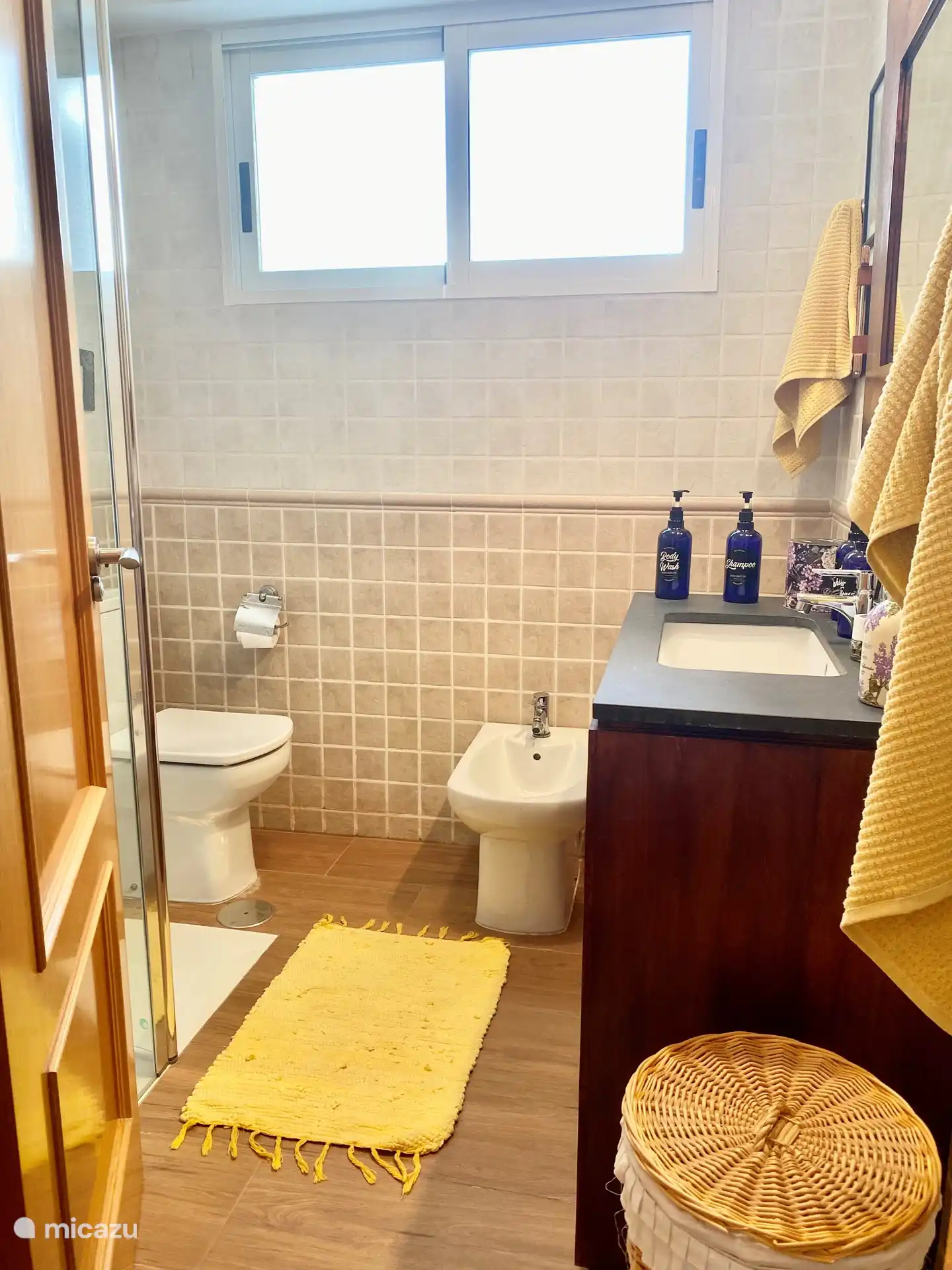 Salle de bain avec douche à l’italienne, toilettes, lavabo et bidet.