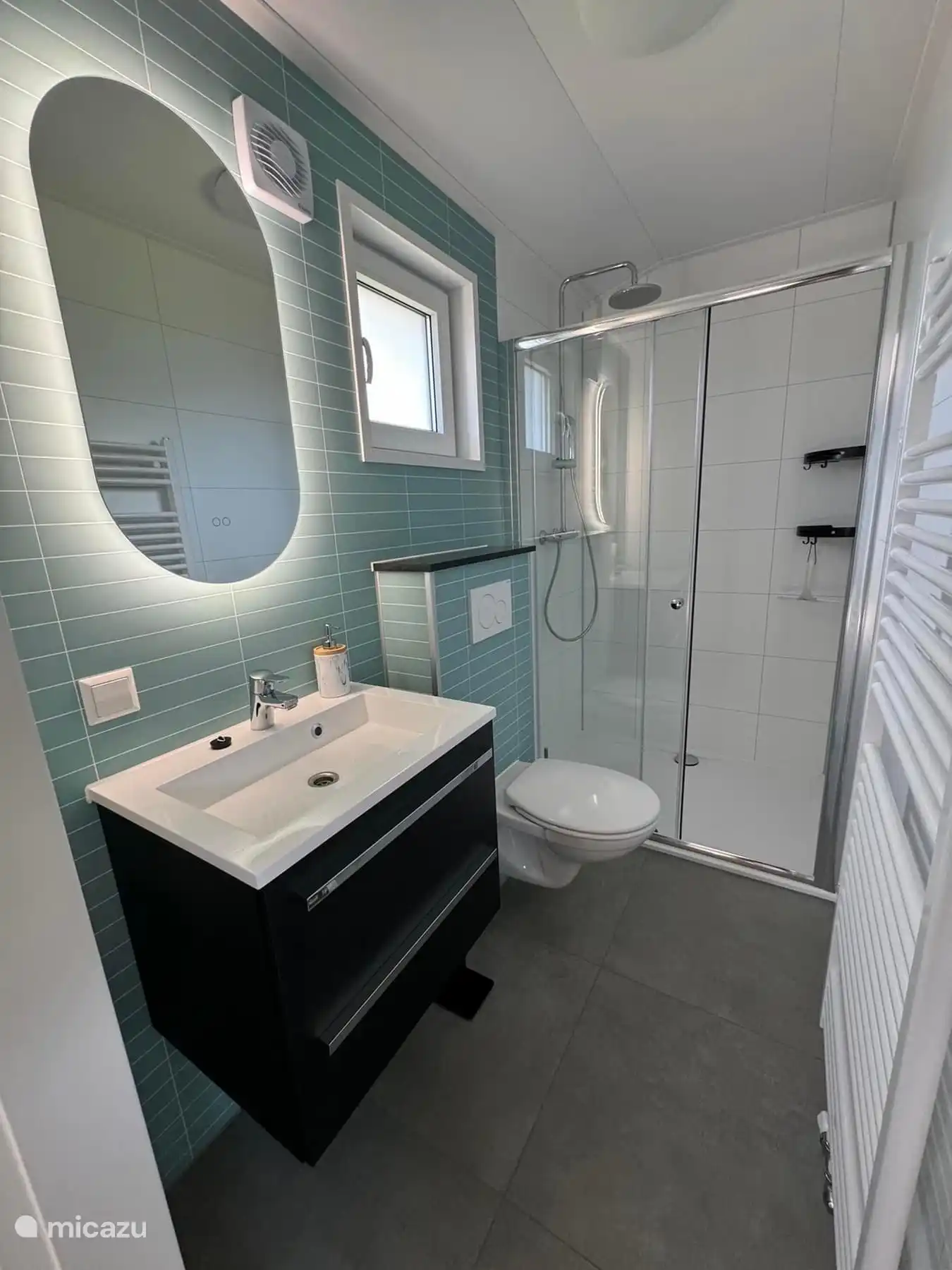 Cuarto de baño con ducha de efecto lluvia y espejo calefactable con iluminación. 