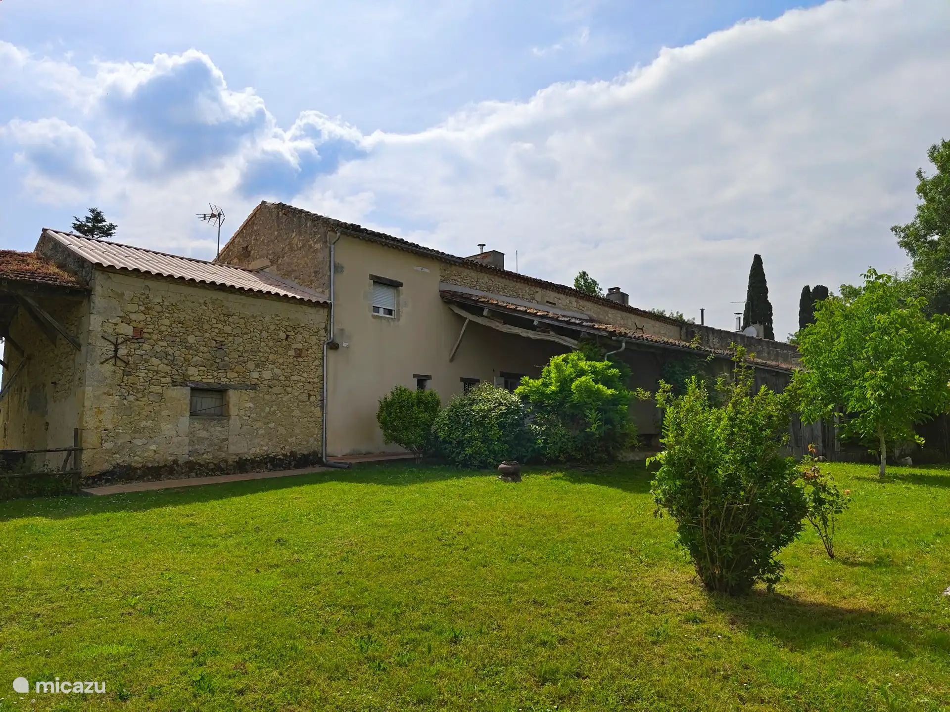 Renoviertes Bauernhaus mit überdachter Terrasse mit Blick auf den Pool und die Umgebung in einem großen Garten