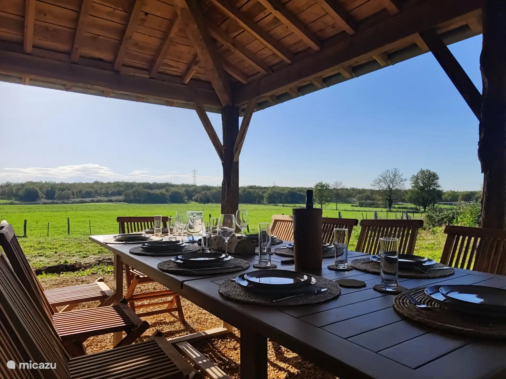Eine überdachte Terrasse mit Blick auf die umliegenden Wiesen