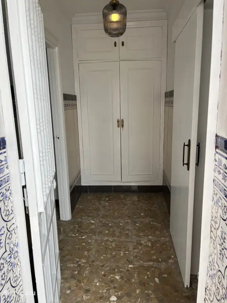 Flur mit Putzschrank. Der Schrank ist während des Aufenthalts verschlossen. Vom Badezimmer aus gehen Sie in den Flur. Hier befindet sich auch eine Tür zur Terrasse und zu Schlafzimmer 2. Von Schlafzimmer 2 aus gelangen Sie über den Innenhof in die Küche und ins Wohnzimmer. Dafür müssen Sie nicht durch Schlafzimmer 1 gehen.