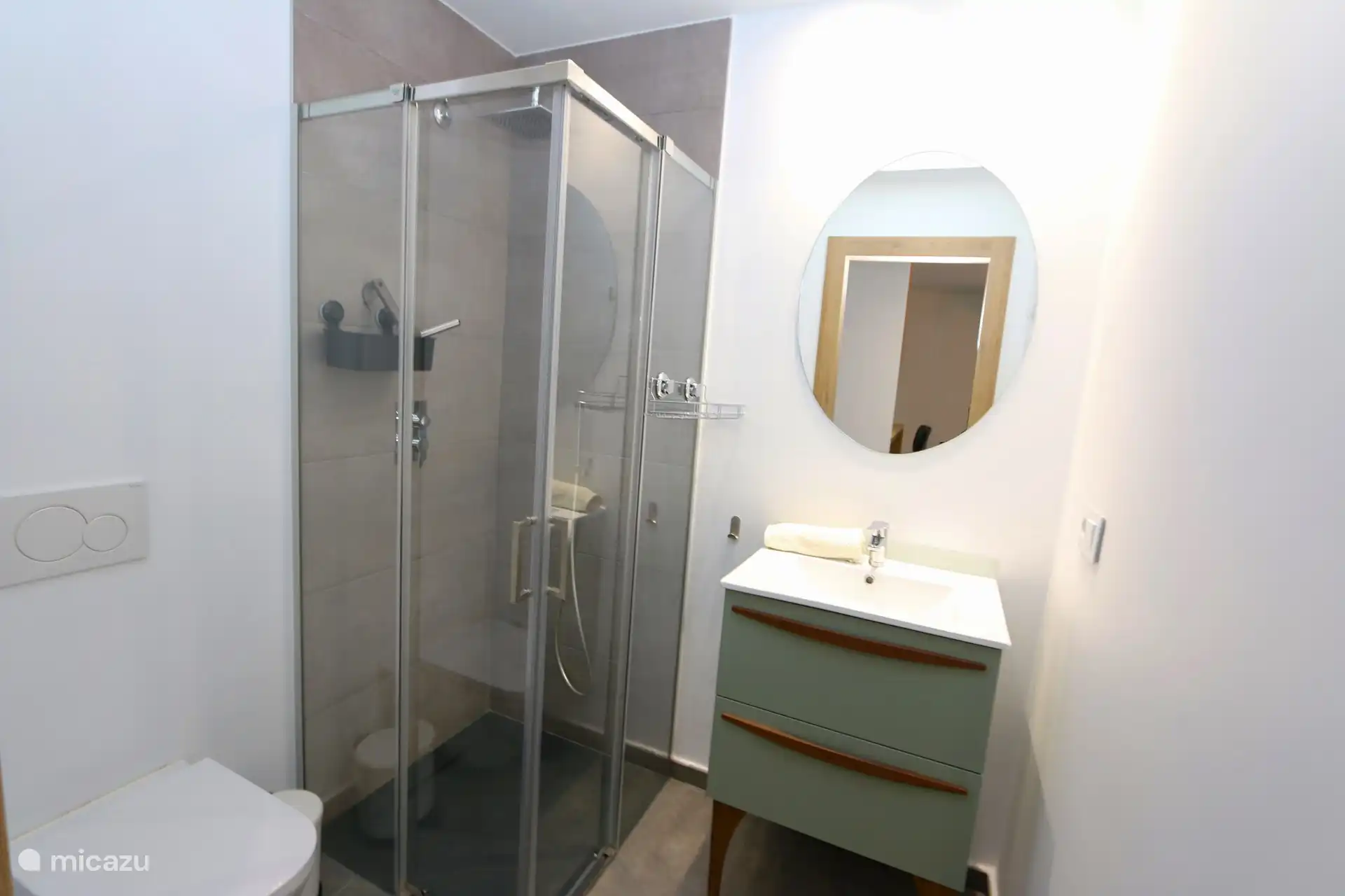 The shower cubicle, laundry stand and toilet of one of the two bathrooms.