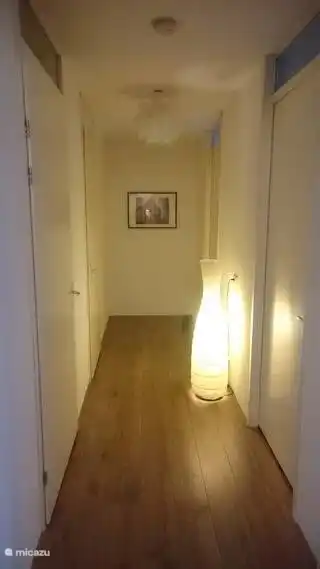 Der Flur, von dem sich auf der rechten Seite das Gästezimmer und auf der linken Seite das Badezimmer befindet. Der Bereich hinter der Lampe ist privat. 