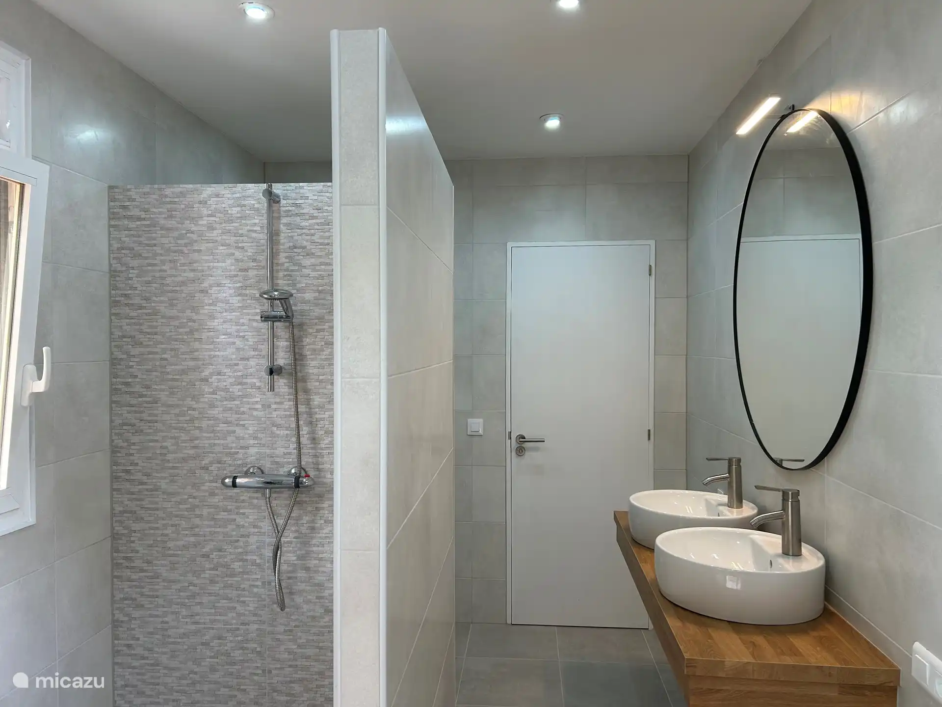 De badkamer 1 met inloopdouche, 2 wasbakken en toilet. Door de schuifpui loop je zo de voortuin in.